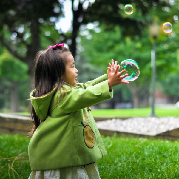 Enfant qui tien une bulle dans un parc