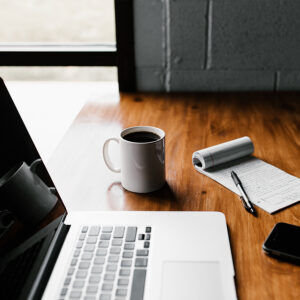 Plan de travail avec un ordinateur, un calepin et une tasse de café